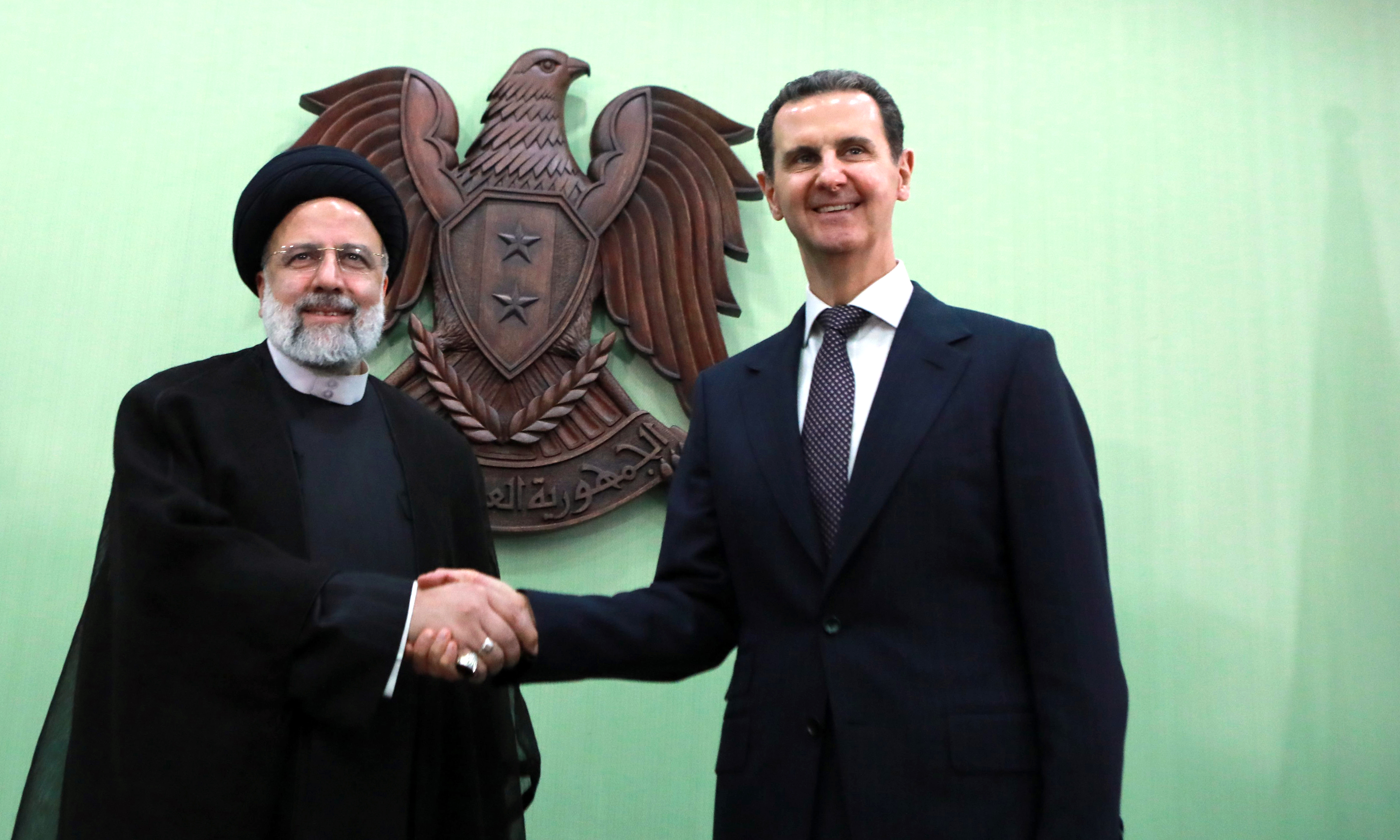 DAMASCUS: Syria's President Bashar al-Assad (R) shakes hands with his Iranian counterpart Ebrahim Raisi in Damascus. – AFP