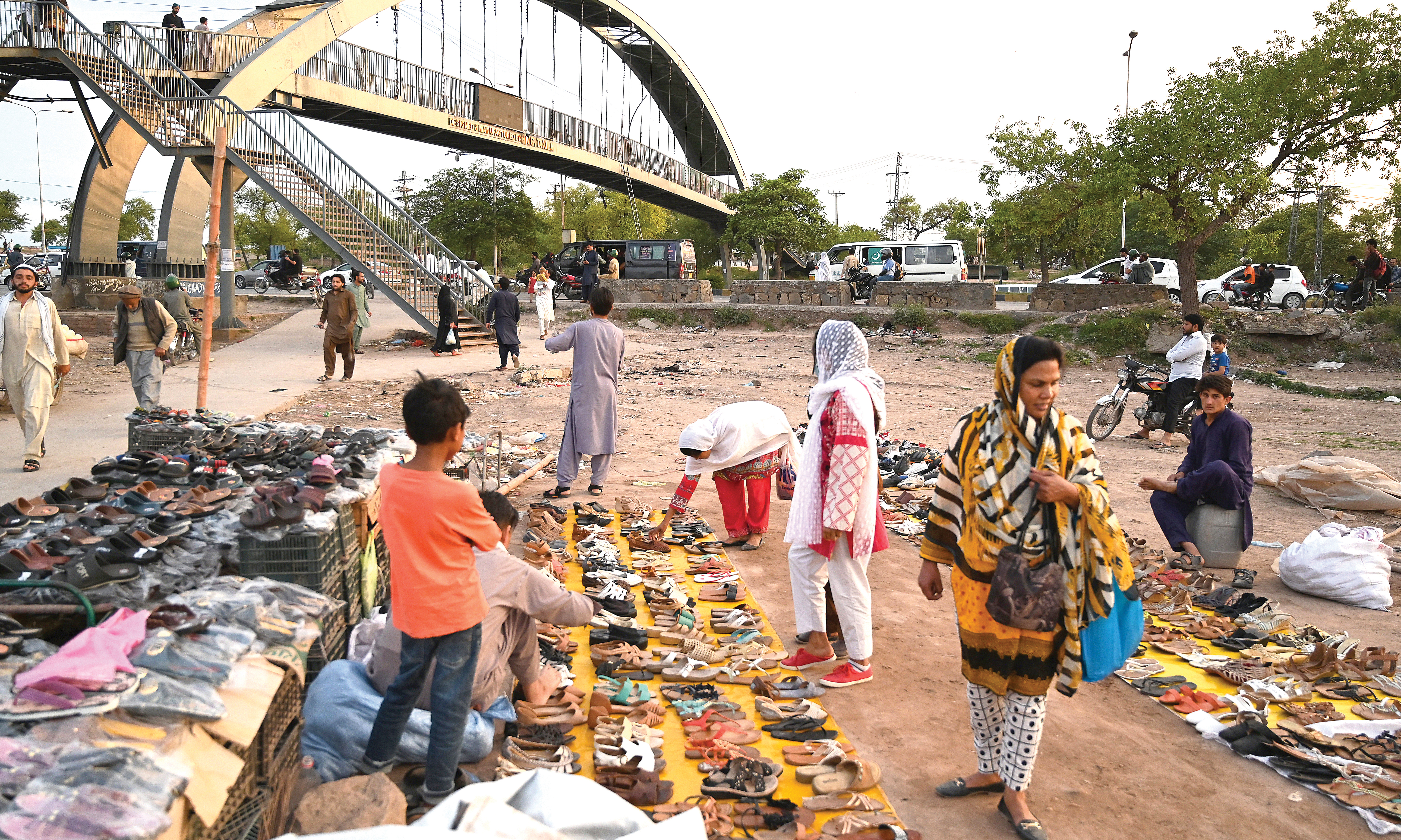 ISLAMABAD: People browse through second hand footwear for sale at a roadside bazaar in Islamabad on May 2, 2023.- AFP