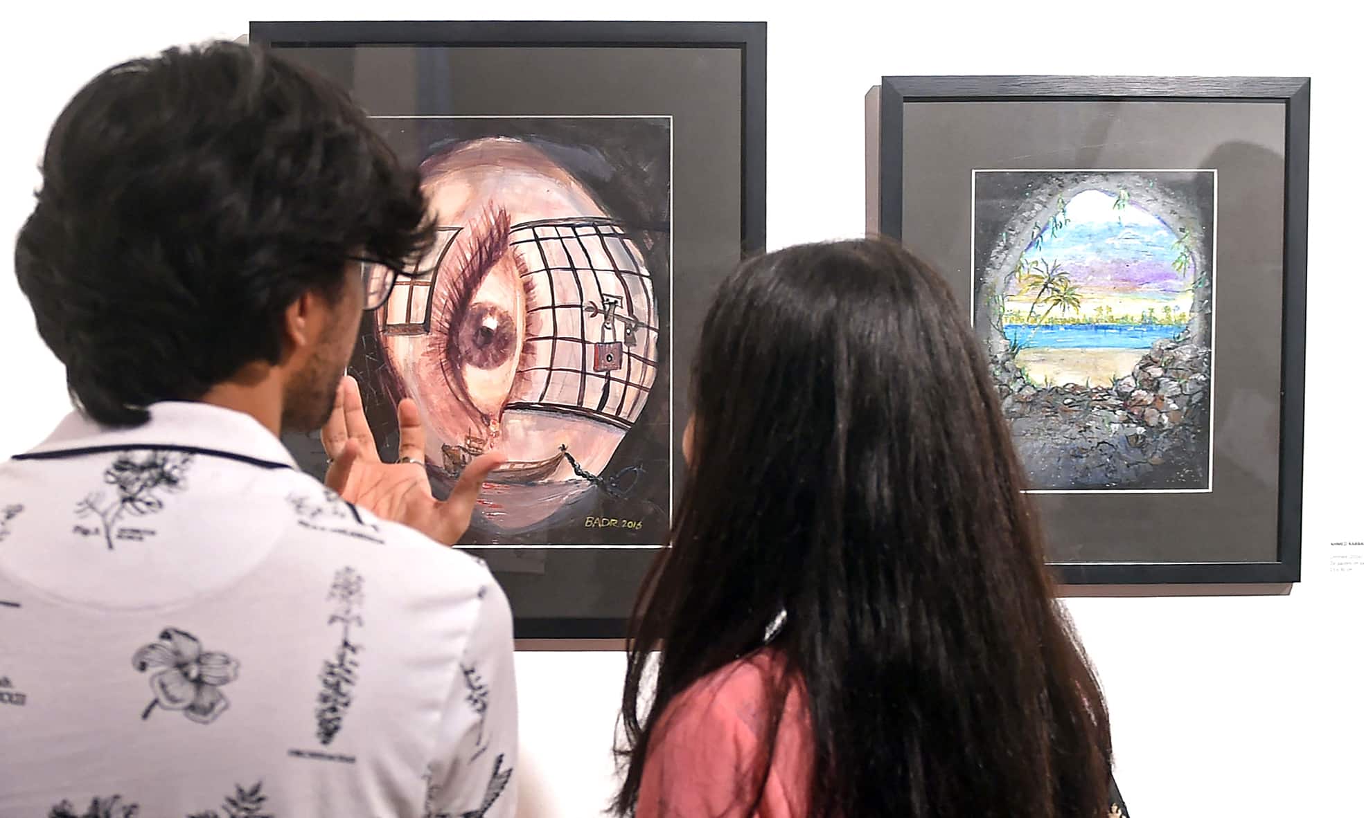 Visitors look at the paintings made by Ahmed Rabbani.