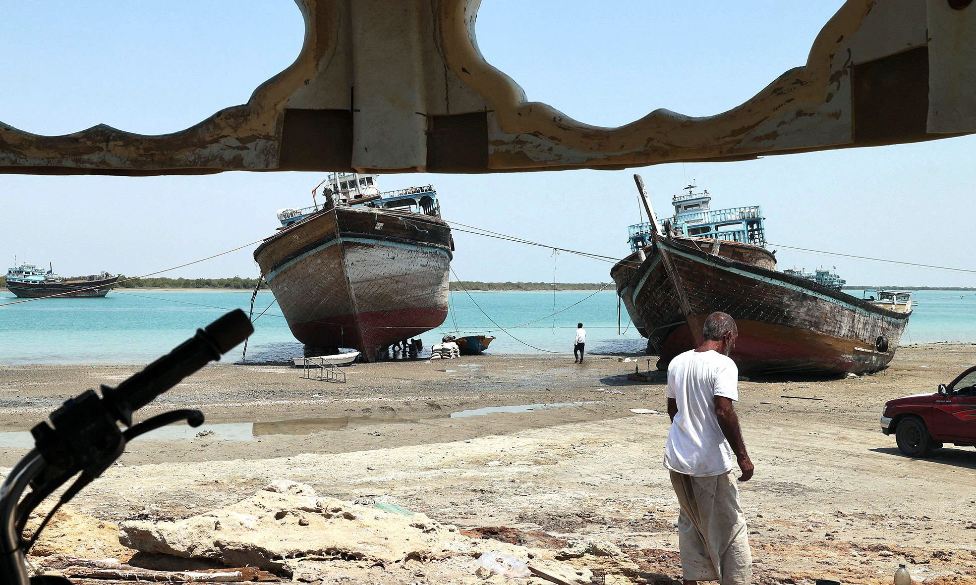 A man walks in front of a traditional wooden ships (lenj), laid ashore for restoration.