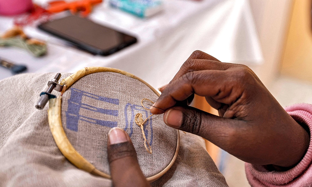 A worker sews a pattern of ancient Egyptian hieroglyphs on a cloth at the Malaika Linens factory.