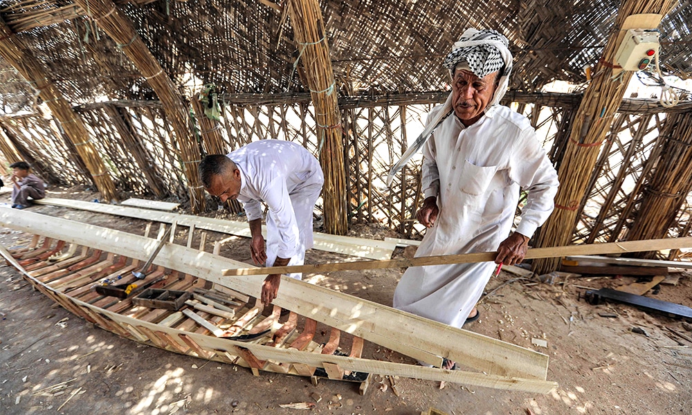 A carpenter hammers beams as he builds a traditional 'meshhouf' wooden boat at a workshop.