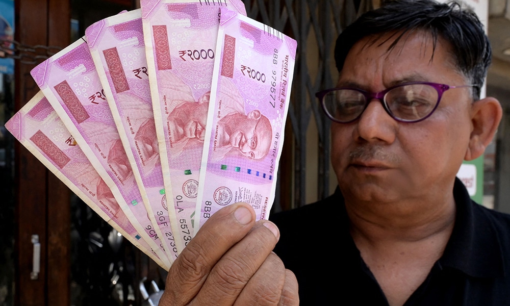 AMRITSAR: A man poses with Indian 2000 rupees currency notes outside a bank in Amritsar on May 20, 2023. -- AFP