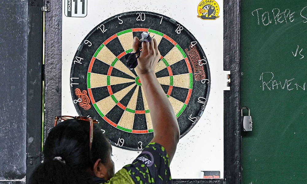 A woman picking up her darts as she competes in a dart competition in Port Moresby.