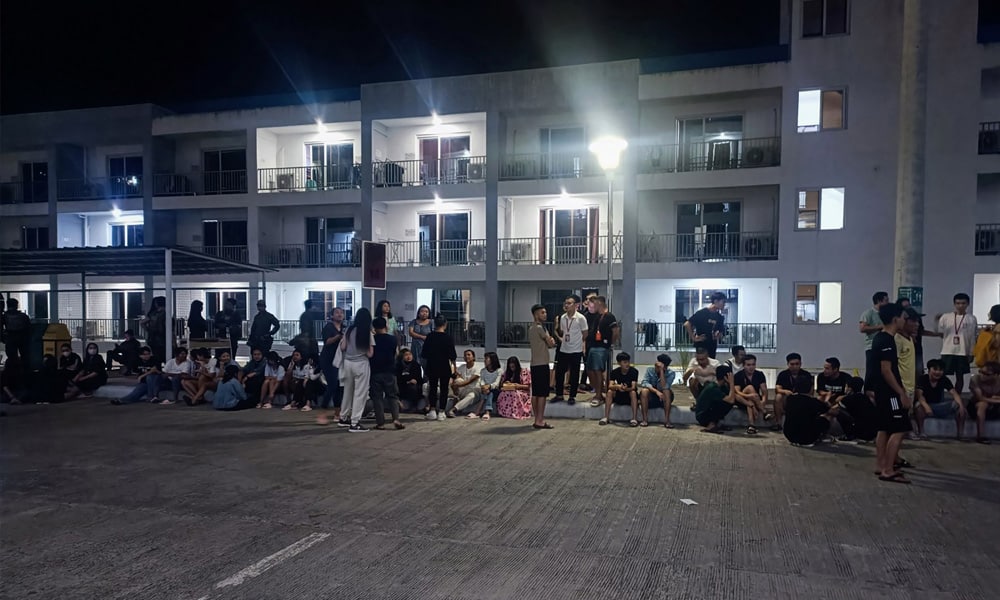 This handout photo taken on May 4, 2023 and received from the Philippine National Police anti-Cybercrime group on May 6 shows rescued trafficked people from Asian countries standing outside a building after a police raid inside a freeport zone in Mabalacat City, in Pampanga province, north of Manila. Philippine authorities have rescued over a thousand people from several Asian countries who were trafficked into the country and forced to run online scams, an official said on May 6.