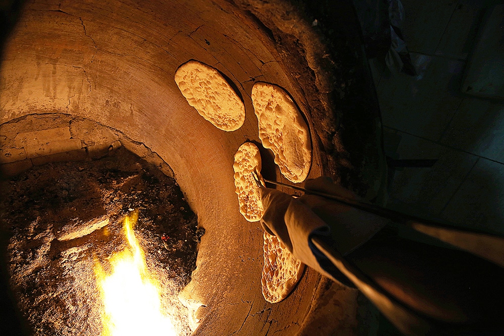 KUWAIT: This photo, taken at a bakery in Souk Al-Mubarakiya, shows the tanoor bread baker's hand as he tries to get the dome-shaped dough as close to the fire as possible. -- Photo by Yasser Al-Zayyat