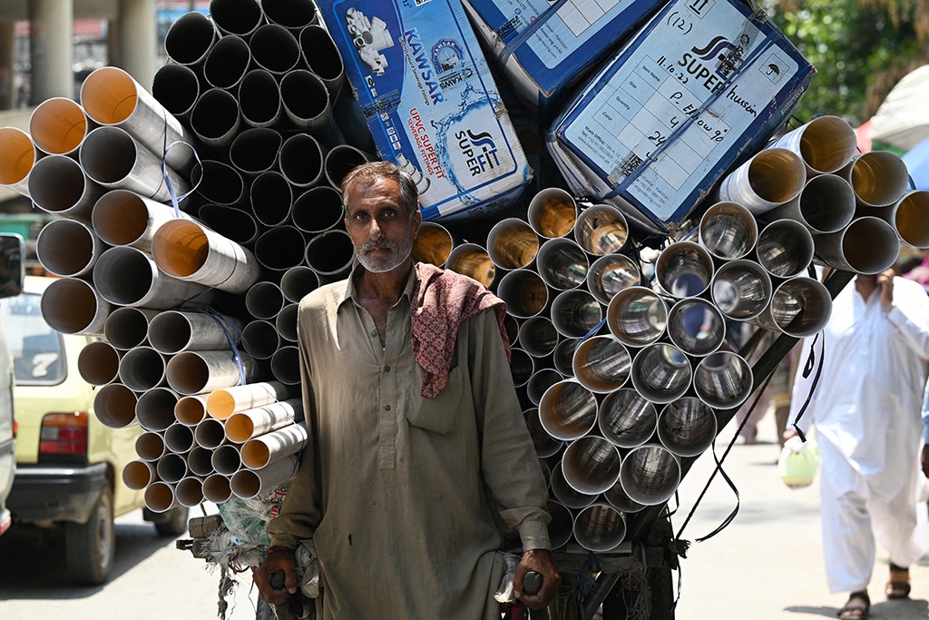 RAWALPINDI: A labourer pulls a handcart loaded with plastic pipes at a market area in Rawalpindi on June 7, 2023. - AFP