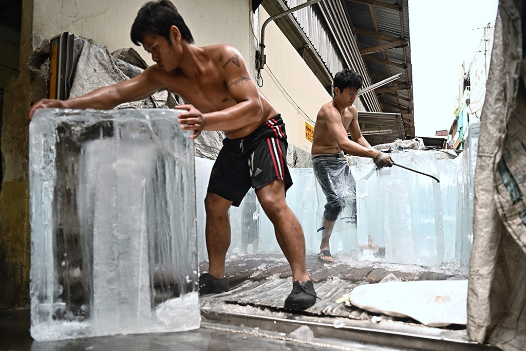BANGKOK: Workers move blocks of ice into a storage unit at a fresh market during heatwave conditions on April 25, 2023. – AFP