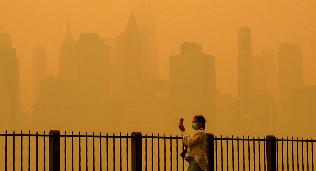 NEW YORK: A person wearing a facemask takes photos of the skyline as smoke from wildfires in Canada cause hazy conditions in New York City on June 7, 2023. – AFP
