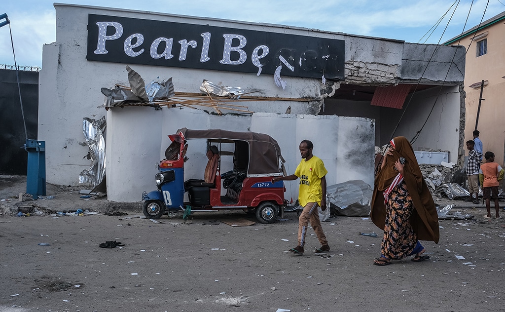 MOGADISHU: Residents walk past a damaged tuk-tuk left outside the site of an attack at the Pearl Beach Hotel in Mogadishu on June 10, 2023. – AFP