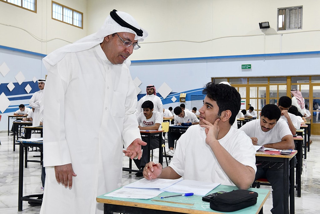 KUWAIT: Education Minister Dr Hamad Al-Adwani checks on a student taking his final exam during an inspection tour he took to a number of schools on Sunday. -- KUNA photos