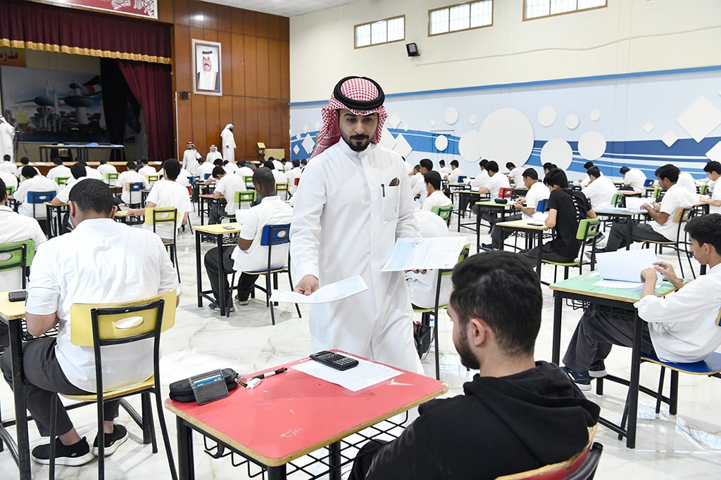 A proctor hands out exam papers to a student sitting for his first final exam for the 2023-2024 academic year on Sunday.