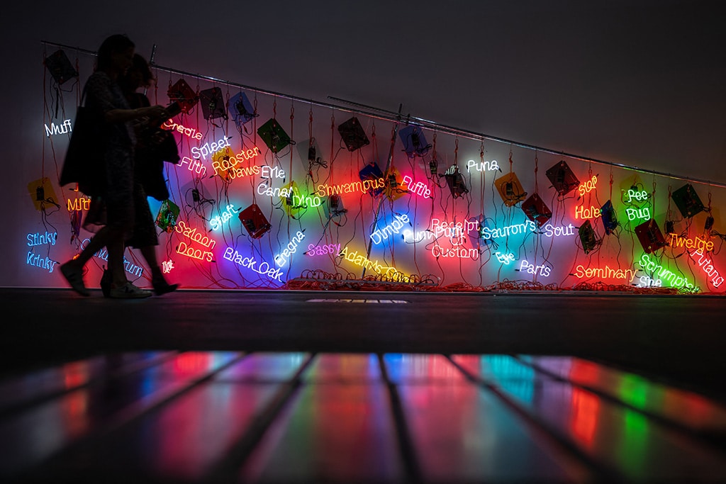 Visitors walk past 'Topa' a 2005 neon installation by US artist Jason Rhoades.