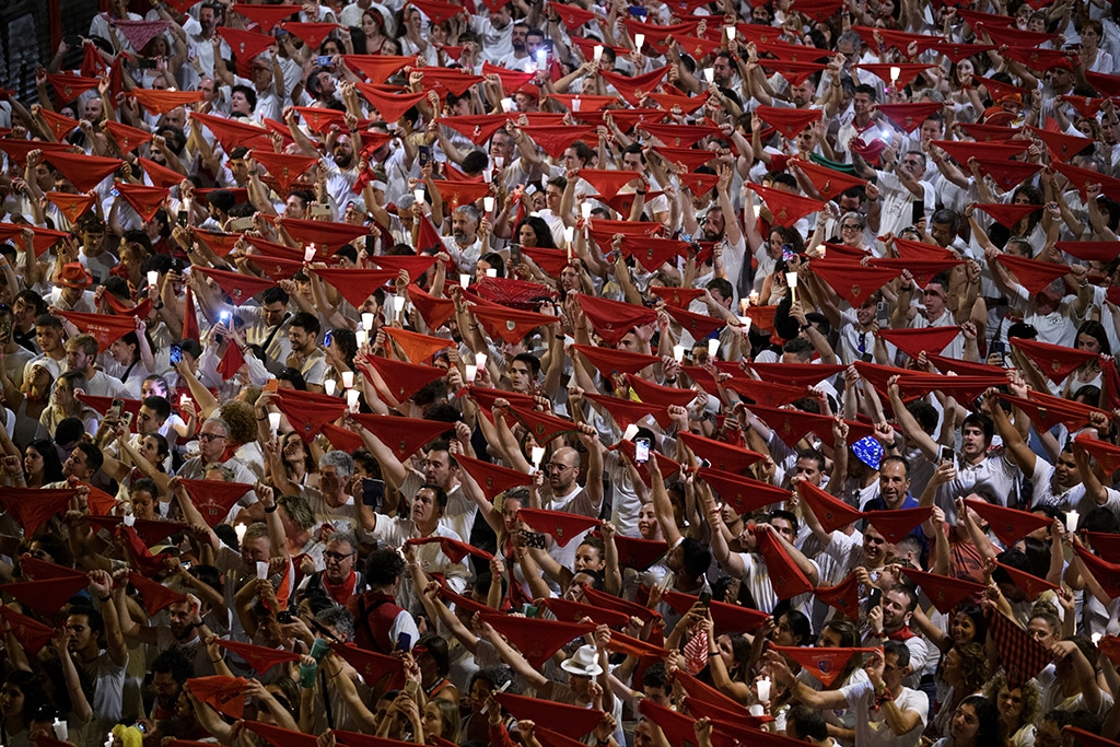 Revelers raise their red scarves and candles as they sing the song 'Pobre de Mi', marking the end of the San Fermin festival in Pamplona.