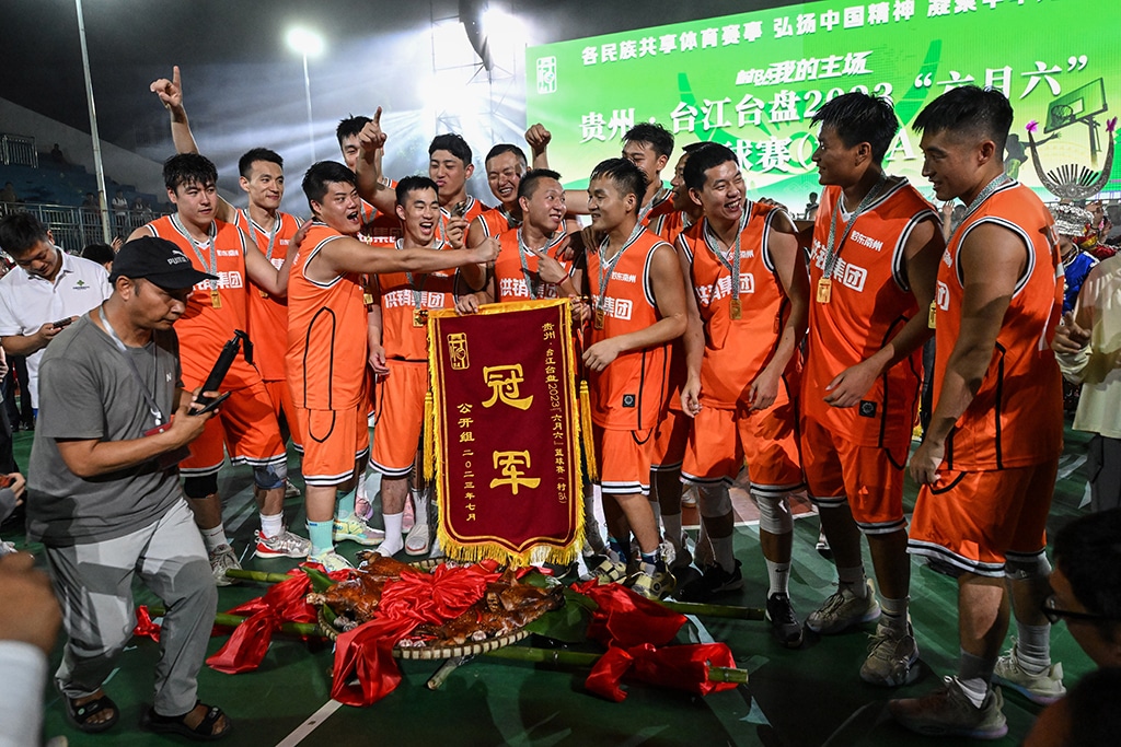 This photo shows members of the winning team posing with a silk banner and their prize of roasted pork after the final in the grassroots basketball competition CunBA in Taipan village, Taijiang county, in southwestern China's Guizhou province.--AFP photos