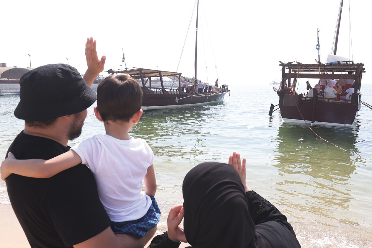 KUWAIT: Family members of a Kuwaiti youth wave as traditional dhows prepare to sail for a pearl diving expedition from the shore of Kuwait City on August 12, 2023. Pearl-diving trips are held annually in summer under the patronage of Kuwait’s Amir, in order to keep alive an ancestral heritage of pearl diving and trading, prior to the discovery of oil.  - Photo by Yasser Al-Zayyat and KUNA