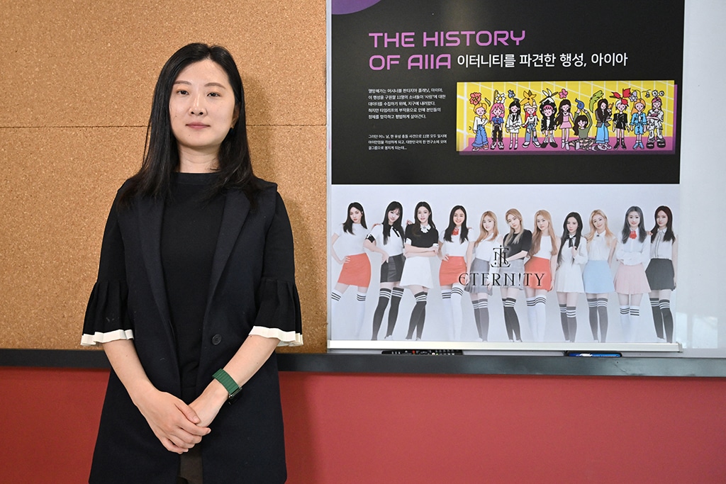 Park Ji-eun, CEO of artificial intelligence company Pulse9, posing with a poster of virtual idol group 'Eternity' during an interview with AFP at her company in Seoul.