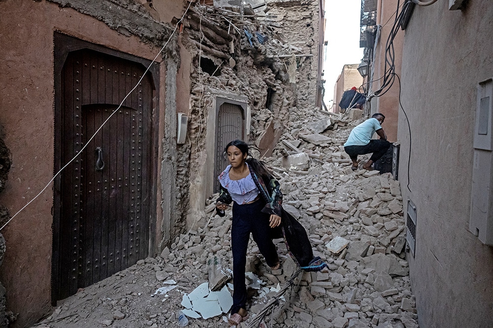 A woman evacuates with her belongings through the rubble in the earthquake-damaged old city of Marrakesh on September 9, 2023. —AFP