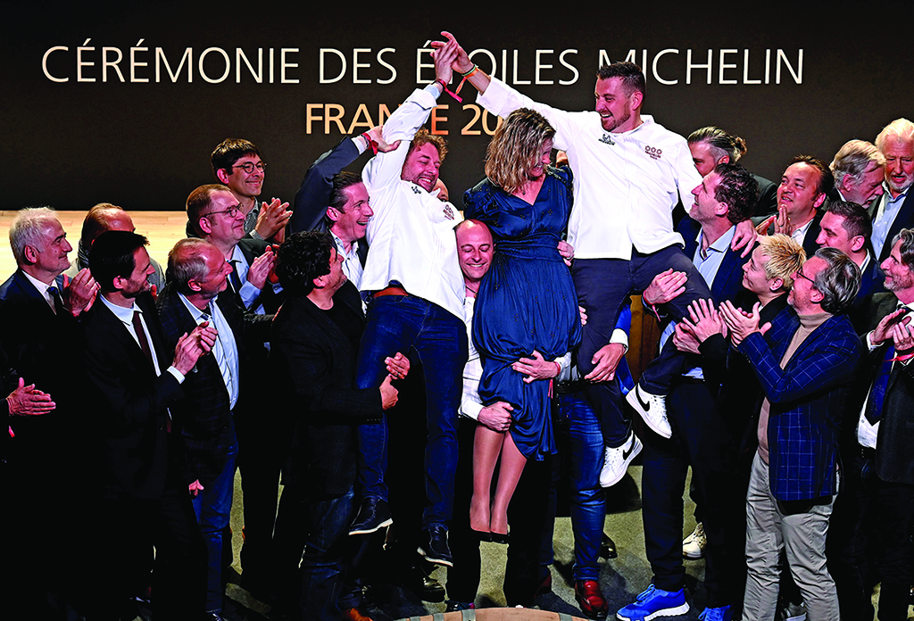 French chef Arnaud Donckele (center left), French chef Dimitri Droisneau (center right) and his wife Marielle Droisneau (center) celebrate after being awarded a third Michelin star during the 2022 edition of the Michelin guide award ceremony at the Avant Scene theatre in Cognac, western France.—AFP photos