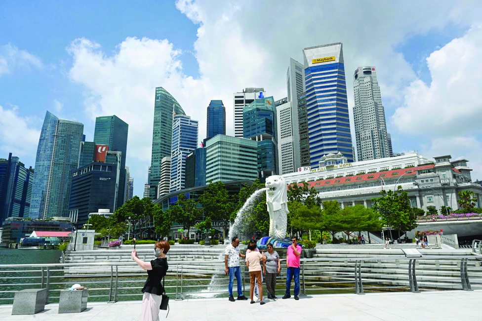 SINGAPORE: People take pictures in front of the Merlion statue in Singapore.-AFP