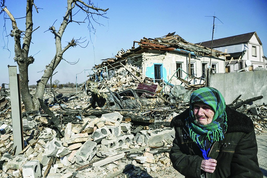 KRASYLIVKA, Ukraine: An elderly woman stands in front of a destroyed house after bombardments in this village east of Kyiv yesterday as Russian forces try to encircle the Ukrainian capital. - AFP