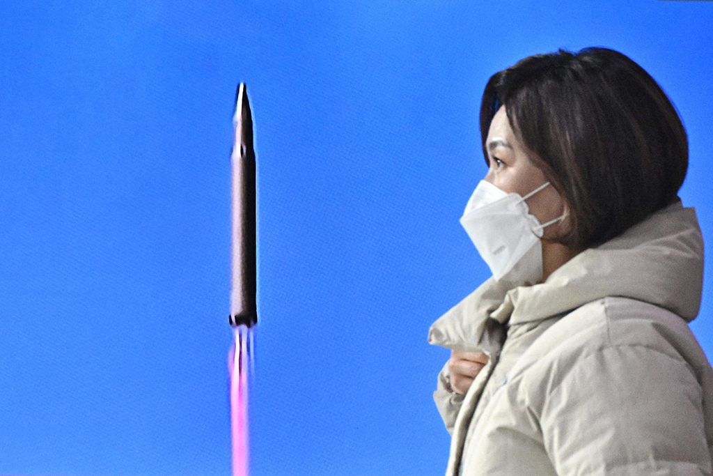 SEOUL: A woman walks past a television report showing a news broadcast with file footage of a North Korean missile test, at a railway station in Seoul on March 24, 2022. - AFP