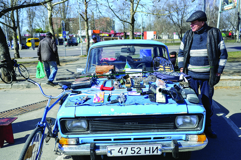MYKOLAIV, Ukraine: A man sells second hand useful items on his 37 years old Soviet car in the center of Mykolaiv, southern Ukraine, on March 22, 2022. The southern city is a key obstacle for Russian forces trying to move west from Crimea to take Odessa, Ukraine's major port on the Black Sea. — AFP