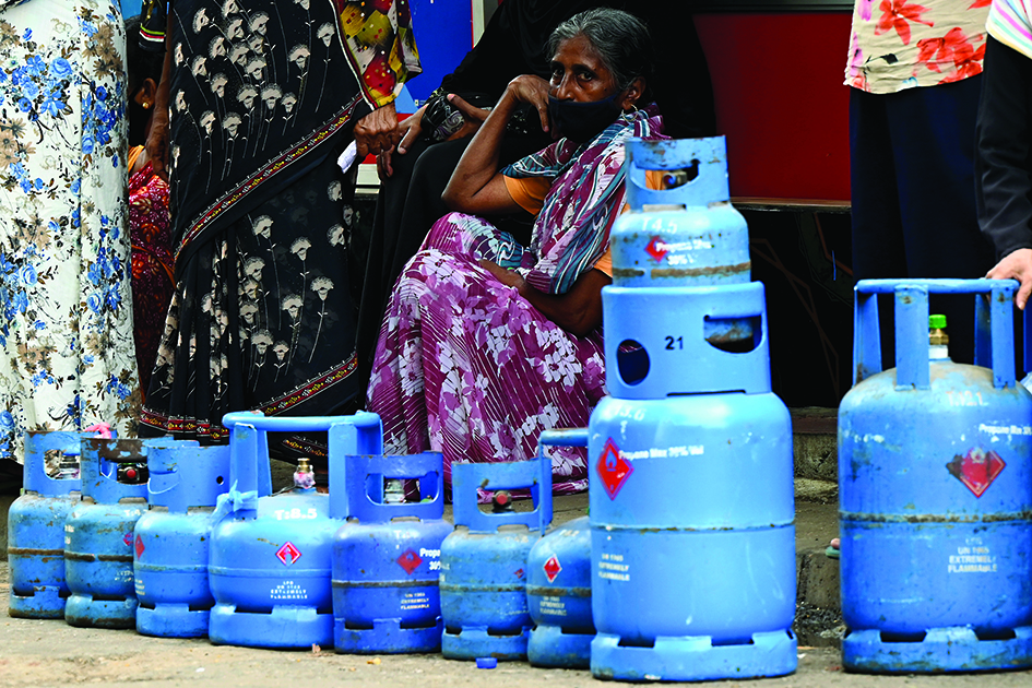 COLOMBO: People queue to buy Liquefied Petroleum Gas (LPG) cylinders following shortages of essentials, in Colombo yesterday.—AFP
