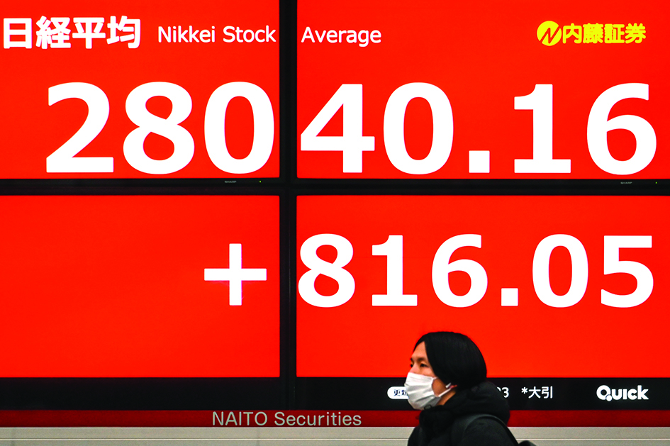 TOKYO: A pedestrian walks past an electronic share price board showing the closing numbers on the Tokyo Stock Exchange in Tokyo on March 23, 2022. – AFP